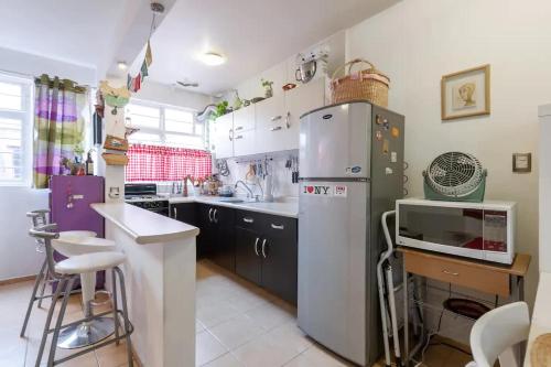 a kitchen with a refrigerator and a counter with stools at Cozy & Full Apt in Coyoacan Great for Long Stays in Mexico City