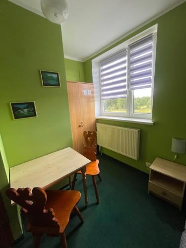 a green room with a wooden table and two chairs at Agroturystyka Radzewicz in Wiżajny