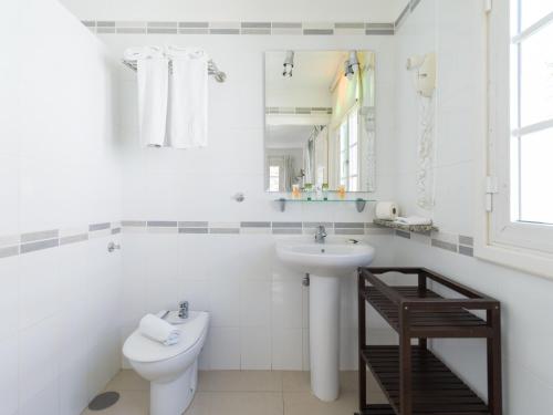 La salle de bains blanche est pourvue de toilettes et d'un lavabo. dans l'établissement Marina nº 48, à Puerto de Mogán
