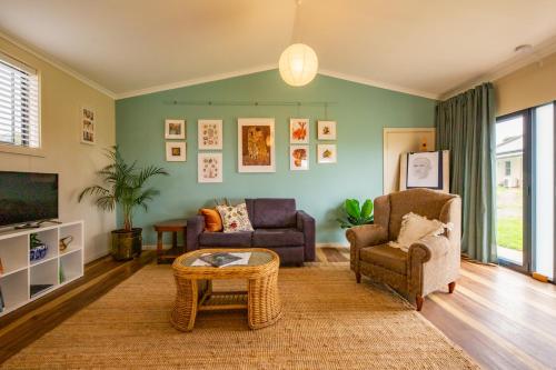 a living room with two chairs and a tv at Meander Retreat - Garden Studio with dog park in Springton