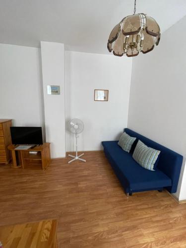 a living room with a blue couch and a fan at Katalinkert Panzió in Győr