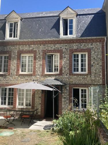 une maison en briques avec une table et un parasol dans l'établissement Maison Etretat à 50 mètres de la plage, à Étretat