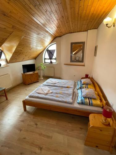 Cama grande en habitación con techo de madera en Katalinkert Panzió, en Győr