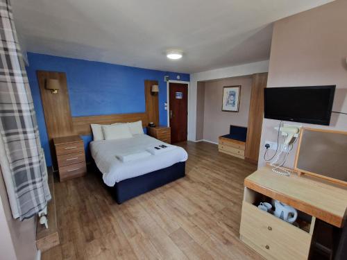 Una habitación de hotel con una cama y un televisor de pantalla plana. en Gilson Hotel, en Hull