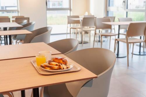 a plate of food on a table with a glass of orange juice at Ibis Budget Mont De Marsan in Mont-de-Marsan