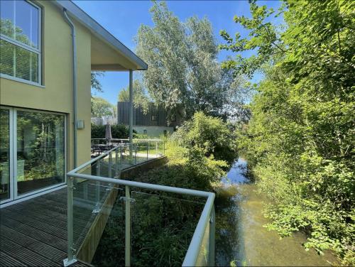 uma vista para um rio a partir da varanda de uma casa em Modern contemporary home in beautiful setting em Somerford Keynes