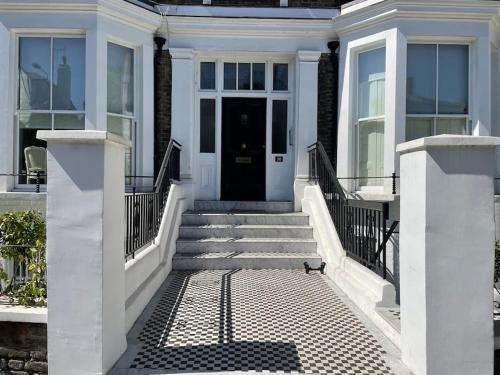 a white house with a cat walking down the stairs at Stylish 3-bedroom flat in Kensington in London