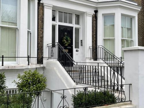 una casa blanca con una puerta negra y escaleras en Stylish 3-bedroom flat in Kensington, en Londres