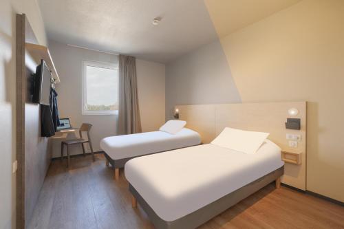 モン・ド・マルサンにあるIbis Budget Mont De Marsanのベッド2台とデスクが備わるホテルルームです。