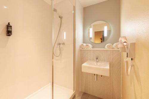 a bathroom with a shower and a sink and a mirror at Ibis Budget Mont De Marsan in Mont-de-Marsan