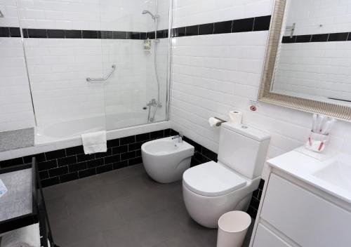 a bathroom with a toilet and a tub and a sink at Venecia Plaza Centro in Valencia