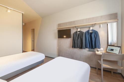 a bedroom with a bed and a desk with a laptop at Ibis Budget Mont De Marsan in Mont-de-Marsan