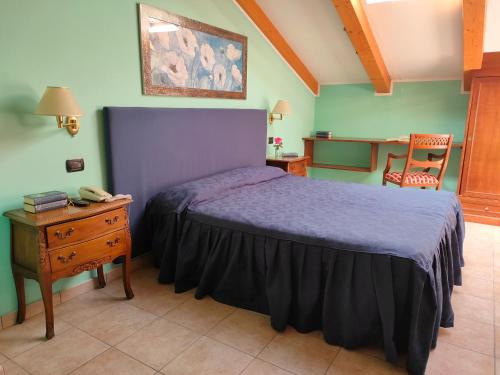 1 dormitorio con 1 cama y 1 mesa con teléfono en Hotel Lion, en Roure Turin
