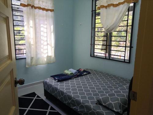 a bed in a room with two windows at UMMI'S Homestay Besut in Kuala Besut