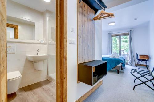 a bathroom with a sink toilet and a bedroom at Hotel Du Lac in Montriond