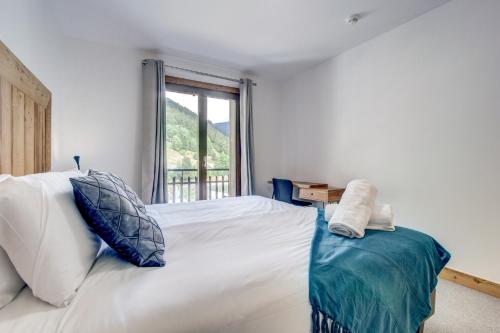 a bedroom with a large white bed with a window at Hotel Du Lac in Montriond