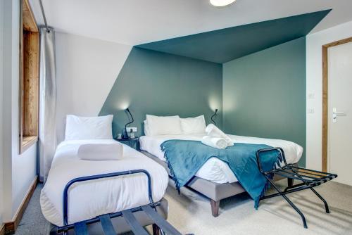 a bedroom with two beds and a blue wall at Hotel Du Lac in Montriond