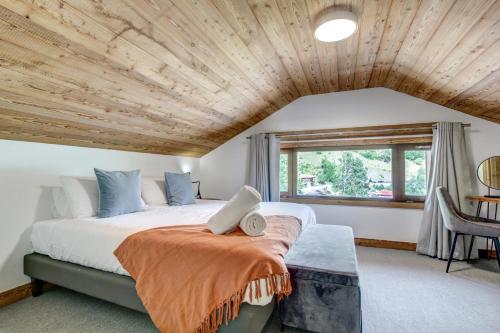 Hotel Du Lac في مونتريون: غرفة نوم بسرير كبير وسقف خشبي