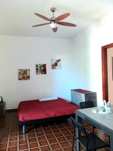 a bedroom with a red bed and a ceiling fan at Villetta Mare in SantʼAndrea