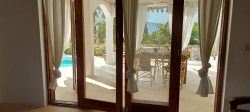 a door leading to a patio with a table and a pool at Namayani apartment in Pwani Mchangani