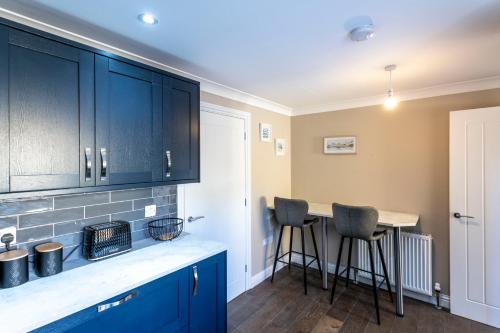 a kitchen with blue cabinets and bar stools at Newly renovated 2 bed house with large garden. in Phillack