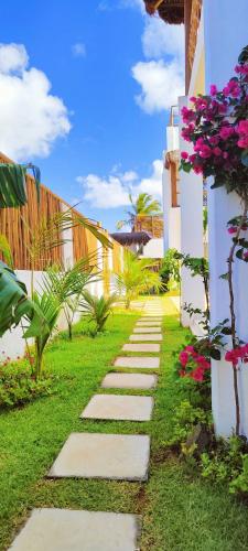 a stepping stone path in a garden with flowers at Sirena Village in São Miguel do Gostoso