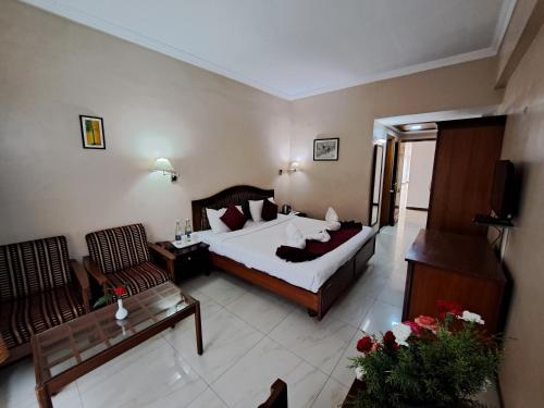 a hotel room with a bed and a living room at Hotel Preethi Classic Towers in Ooty