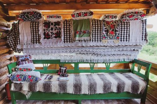 a green bench with blankets and pillows on it at Pensiunea Teodora Breb Maramu in Breb