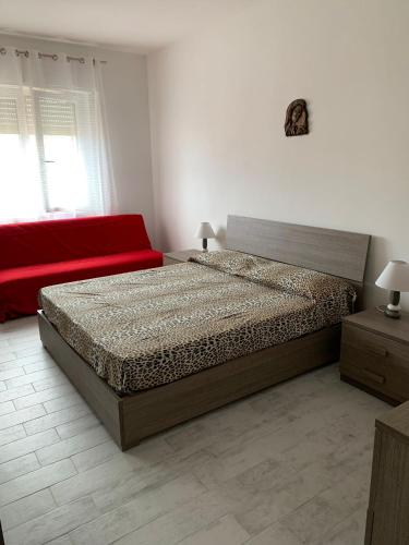 a bedroom with a bed and a red couch at Appartamento SanBart Mare in San Bartolomeo al Mare