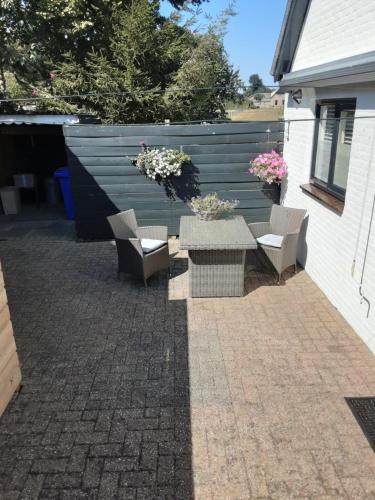a patio with a table and chairs and flowers at Appartement nabij Elburg in Zwarteweg