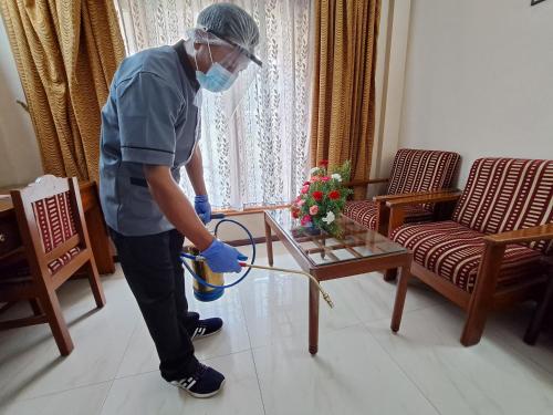 a man in a room with a table with a vacuum at Hotel Preethi Classic Towers in Ooty