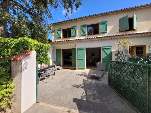 una casa con puertas verdes y una valla en Villa 78 m2 - Au Chant des Cigalous, en Six-Fours-les-Plages