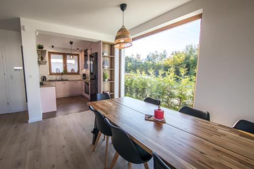 a dining room with a wooden table and a large window at Dom na wzgórzu z widokiem na morze etezje in Mechelinki