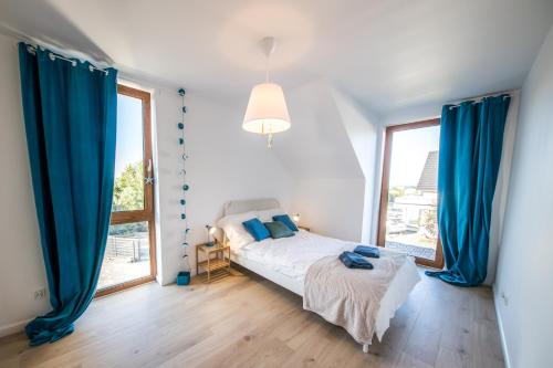 a bedroom with a bed with blue drapes and a window at Dom na wzgórzu z widokiem na morze etezje in Mechelinki