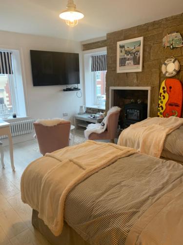 um quarto com 2 camas, uma televisão e uma lareira em Coastal Joy - Family and friends bedrooms em Newbiggin-by-the-Sea