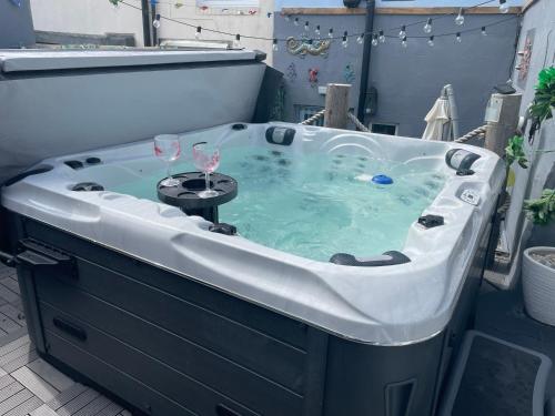 a hot tub with two wine glasses in it at Coastal Joy - Family and friends bedrooms in Newbiggin-by-the-Sea