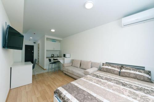 een slaapkamer met een bed en een bank en een keuken bij Cozy SmartHouse in Kiev