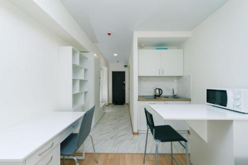 een keuken met witte werkbladen en een tafel en stoelen bij Cozy SmartHouse in Kiev
