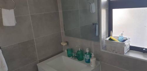 a bathroom with a sink and a shower with a mirror at Sarona city Habitat Alpha apartments C202 Gaborone in Gaborone