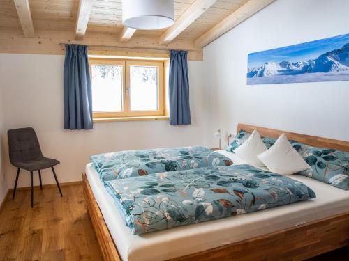 ein Schlafzimmer mit einem Bett mit einer blauen Bettdecke und einem Stuhl in der Unterkunft Ferienwohnung Schwendle Egg in Mittelberg