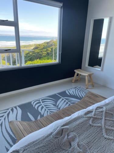 a bedroom with a bed and a large window at TAKE TWO lovely beach apartment, Great Brak River in Groot Brak Rivier