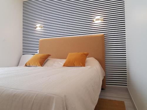 een slaapkamer met een bed met witte lakens en oranje kussens bij COTE JARDIN - CANCALE - GITE STANDING - PROCHE CENTRE ET PORT in Cancale
