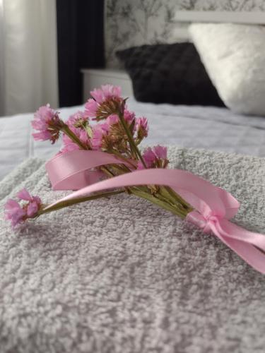 a pink flower with a pink ribbon on a bed at Apartament nad Jeziorakiem in Iława