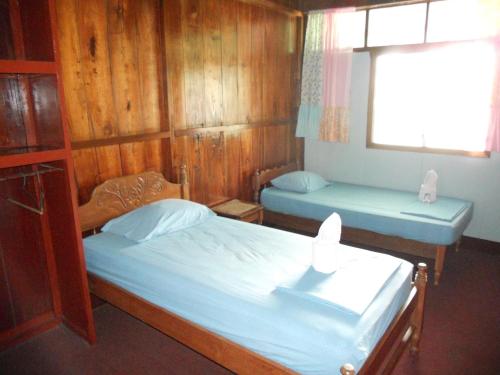two beds in a room with wooden walls and a window at Cabinas Leyko in San Carlos