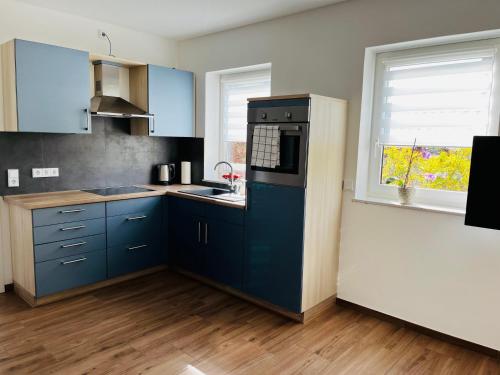 a kitchen with blue cabinets and a sink and a window at Casa Caro in Prüm