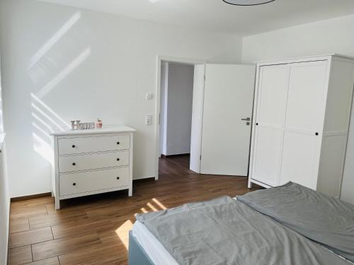 a white bedroom with a bed and a dresser at Casa Caro in Prüm