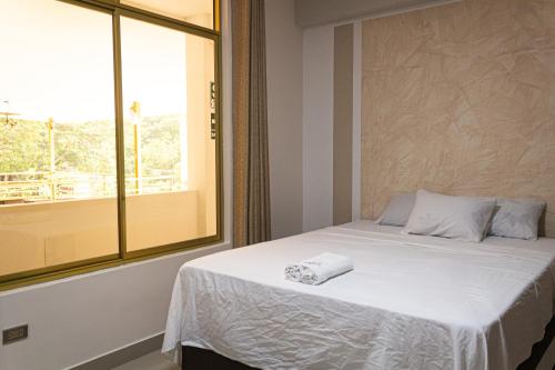 a bedroom with a white bed with a window at Green House Tarapoto in Tarapoto