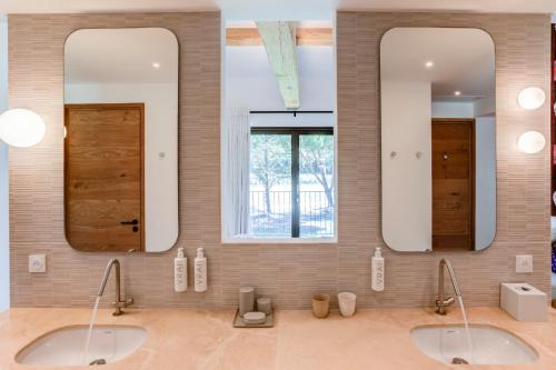 two sinks in a bathroom with two mirrors at Domaine de Panery in Pouzilhac