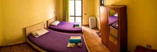 2 camas púrpuras en una habitación con espejo en Haka Guesthouse, en Golem