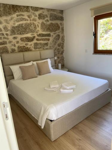 a bedroom with a large bed with a stone wall at Casa do capitão A casa ideal para férias no Gerês in Vieira do Minho